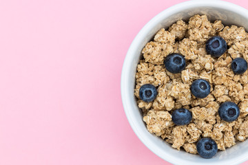 Breakfast cereal granola muesli bowl with blueberries fruit on pink background