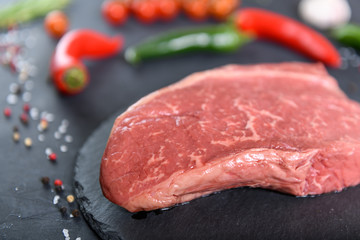 Raw fresh marbled meat and seasonings on dark background