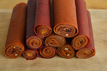 Sweet pureed fruit pastille.Fruit roll-ups homemade on a wooden background . Natural sweets from dried berries and fruits. healthy snack concept
