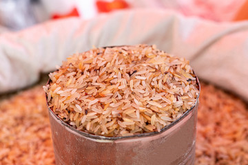 Brown rice in a bowl on a pile of brown rice.