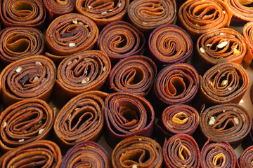 Sweet pureed fruit pastille.Fruit roll-ups homemade on a wooden background . Natural sweets from dried berries and fruits. healthy snack concept