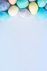 Colorful Easter eggs dyed by colored water with beautiful pattern on a pale blue background, design concept of holiday activity, top view, copy space.