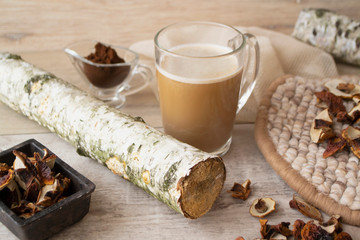 Mushroom chaga coffee latte superfood trend. Dry cep mushrooms, chaga and coffee powder. Caffeine latte, cappuccino drink, hipster. Wooden light background, branch of birch