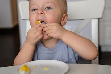 Little boy is eating a boiled egg. Easter breakfast