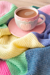 Knitted effect cup with cappuccino, colorful pastel giant plaid, morning concept, vertical image