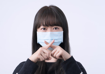 Portrait of young Asian woman, saying no to coronavirus infection with wearing medical surgical blue face mask isolated on white background, close up, closeup.