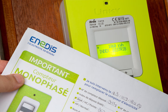 Hand holding the opening contract for a linky box ERDF (Electricity Network Distribution France) in the entry of Building