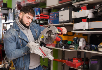 male engineer chooses circular saw in tool store
