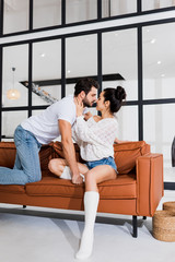 Smiling woman kissing boyfriend on couch in living room