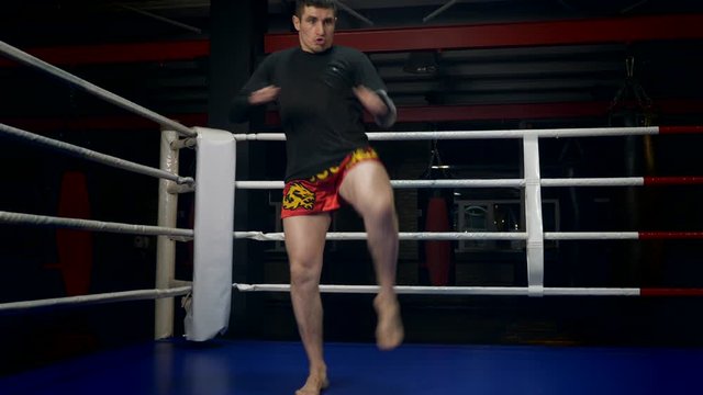 Slow motion Muay Thai Fighter Blows Fast Forceful Thrusts with the Foot. Training Kicks In Boxing Ring At Gym
