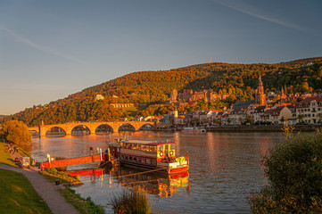 Fototapeta premium Stunning reddish sunset over the old town, castle and main city bridge in Heidelberg, Germany, panoramic view
