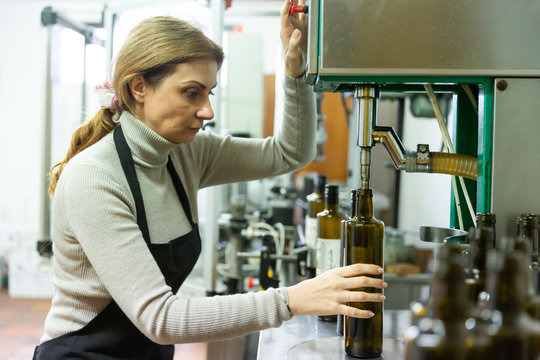 Woman controlling bottling of olive oil