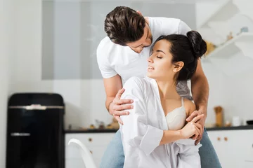 Man hugging attractive girlfriend in shirt and bra in kitchen © LIGHTFIELD STUDIOS