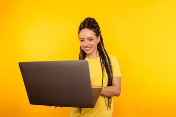 Portrait of happy exited young lady with laptop isolated over the yellow studio