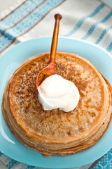 pancakes with sour cream are stacked on top of each other on a blue plate
