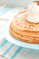 pancakes with sour cream are stacked on top of each other in close-up