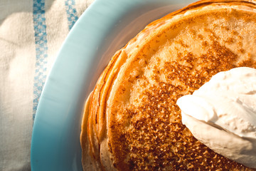 pancakes with sour cream are stacked on top of each other on a blue plate