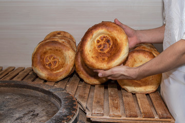 A baker holds in his hands a flat bread baked in the oven.