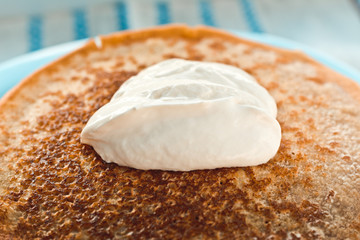 pancakes with sour cream are stacked on top of each other in close-up