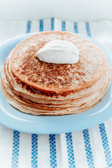 pancakes with sour cream are stacked on top of each other on a blue plate