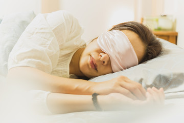 Woman sleeping on bed with eye mask on.