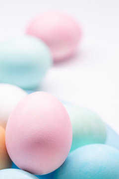Huevos de pascua de colores en plato azul sobre fondo blanco