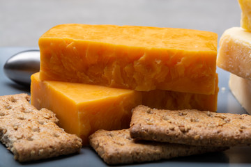 Cheese collection, matured and orange original British cheddar cheese in blocks served on grey plate