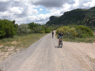 Two women riding a bike on a dirt road in nature