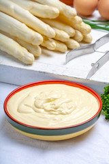 White hollandaise sauce in bowl, traditional sauce for dishes with cooked white asparagus