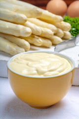 White hollandaise sauce in bowl, traditional sauce for dishes with cooked white asparagus