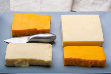 Cheese collection, matured and orange original British cheddar cheese in blocks served on grey plate