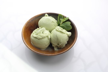 Scoops of green tea, pistachio ice cream in a bowl. Dessert isolated on white.