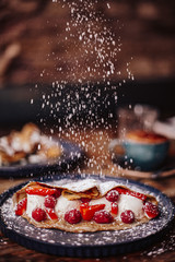 Shrove Tuesday, Pancake Day. Action shot of delicious pancakes served with fresh strawberries, vanilla ice cream and icing sugar. Concept of English traditions and food.