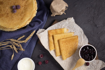 Stack of pancakes for Shrovetide with honey and jam, top view. On a wooden Board in the Russian style