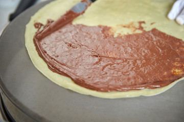 Putting chocolate sauce on crepe 