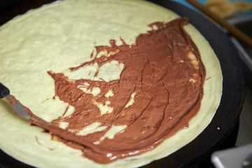 Putting chocolate sauce on crepe 