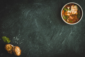 green lentil soup with tomatoes and vegetables on a dark background on the table. copy space horiizontal