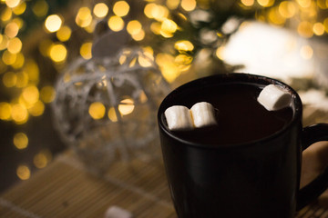 Strong coffee in a black mug. A white marshmallow drops into the mug from above. The liquid splashes in different directions