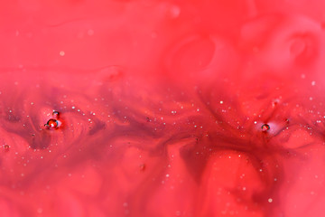 red and purple alcohol ink with glitter in water, abstract background, macro view