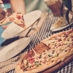 Female hand taking slice of fresh pizza in modern cafe