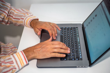 Fototapeta na wymiar Man using laptop, downward view, focus on hands and keyboard
