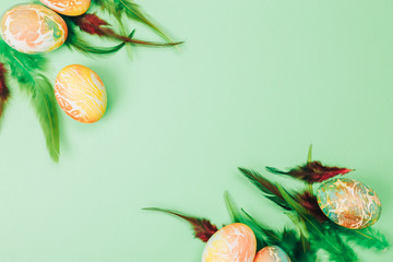 Easter eggs painted in orange and green colors on yellow background, flat lay, space for text