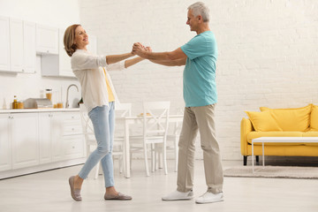Fototapeta premium Happy senior couple dancing in kitchen at home