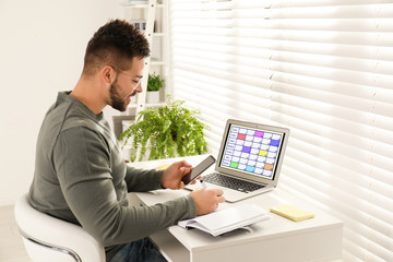 Young man planning his schedule with calendar app on laptop in office