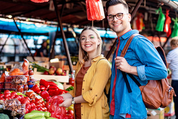 Obraz premium Beautiful young couple buying fresh vegetables on outdoor market.
