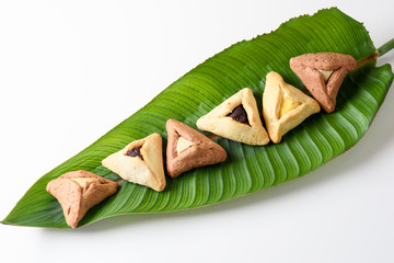 Group of variety cookies traditional meal for Jewish Holiday Purim on palm leaf. Hamantaschen triangular pastries also called Haman's pockets or Oznei Haman-Haman's ears.