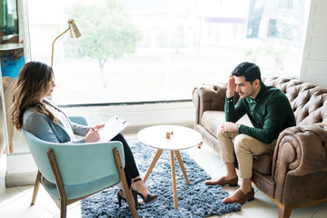 Therapist Guiding Sad Male Professional In Office