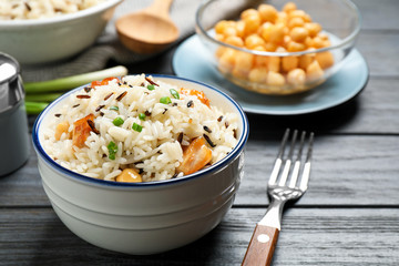 Delicious rice pilaf with chicken on black wooden table