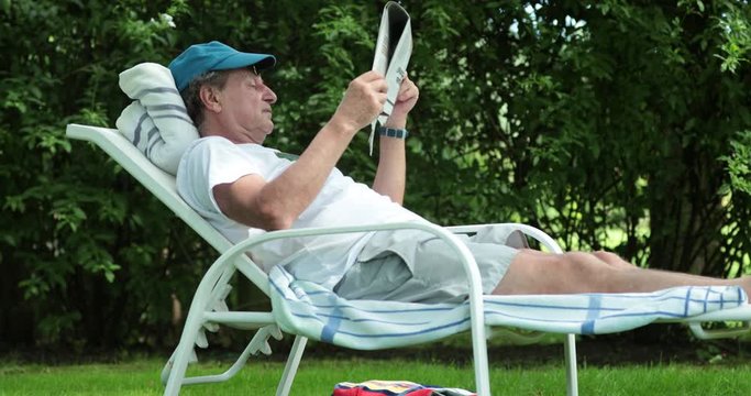 Candid senior man reading newspaper outdoors