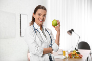 Nutritionist with fresh apple in her office